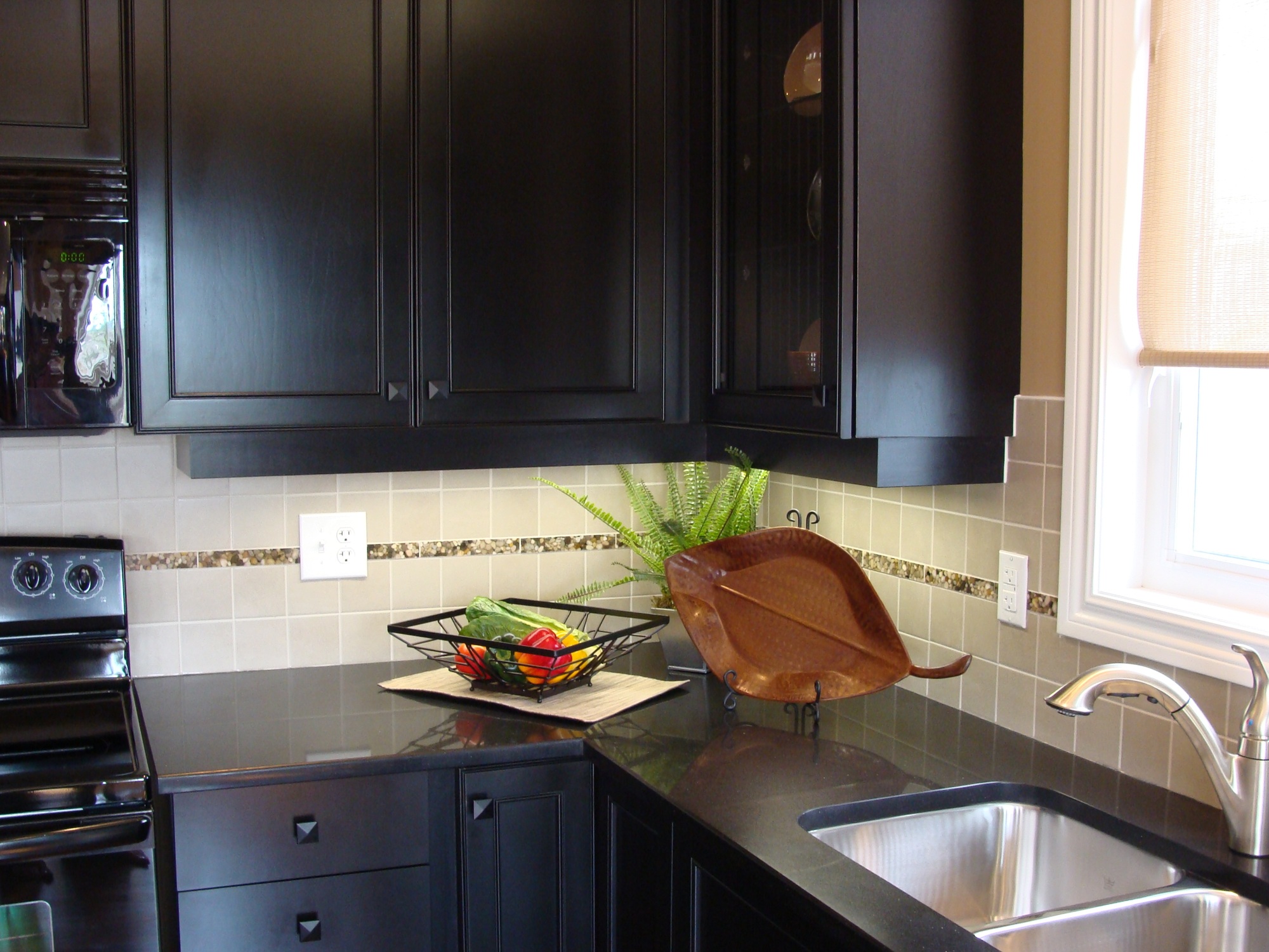 Modern kitchen design in dark color for visual impact, black granite countertops, undermount sink